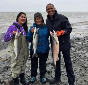 أوباما يأكل سمكة سلمون بدأ بالتهامها دب في ألاسكا
